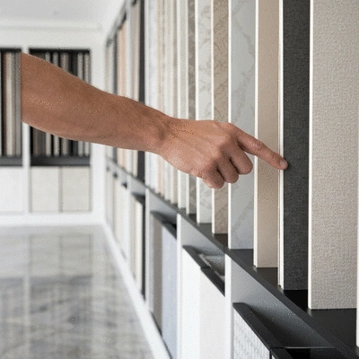 Hand reaching for a wallpaper sample from a selection in a showroom, no text, no words, no typography, clean image
